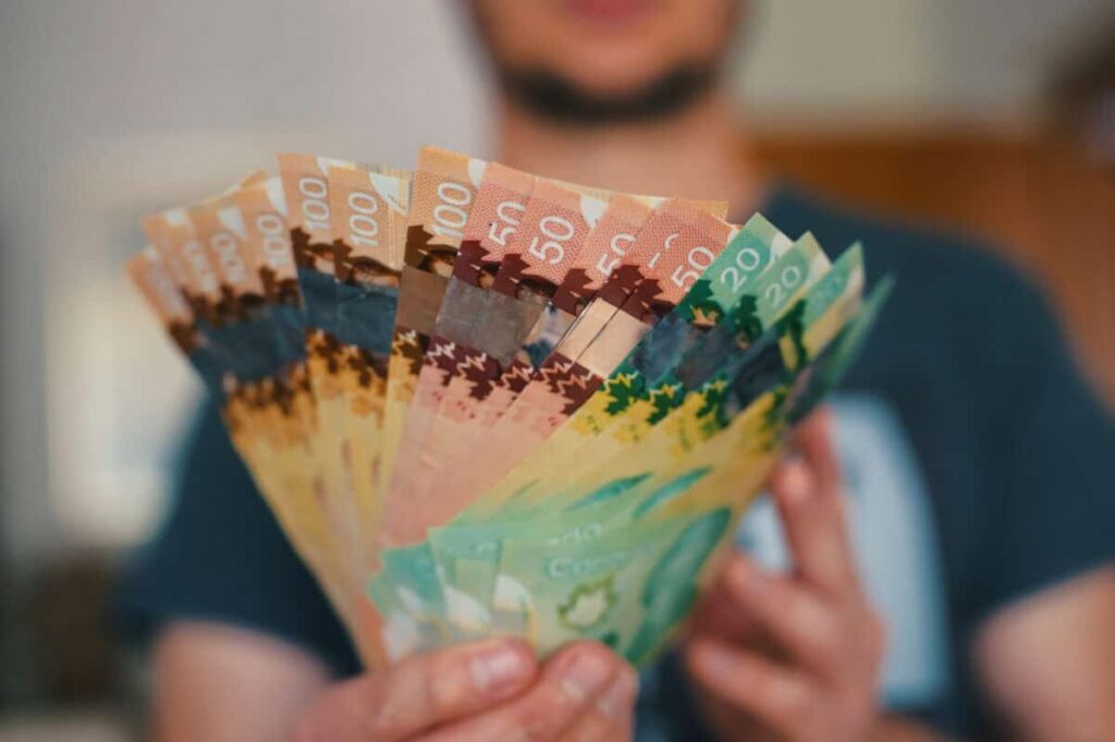 I’d Put My Whole 2026 TFSA Contribution Into this 5.5% Passive-Income Payer Person holds banknotes of Canadian dollars